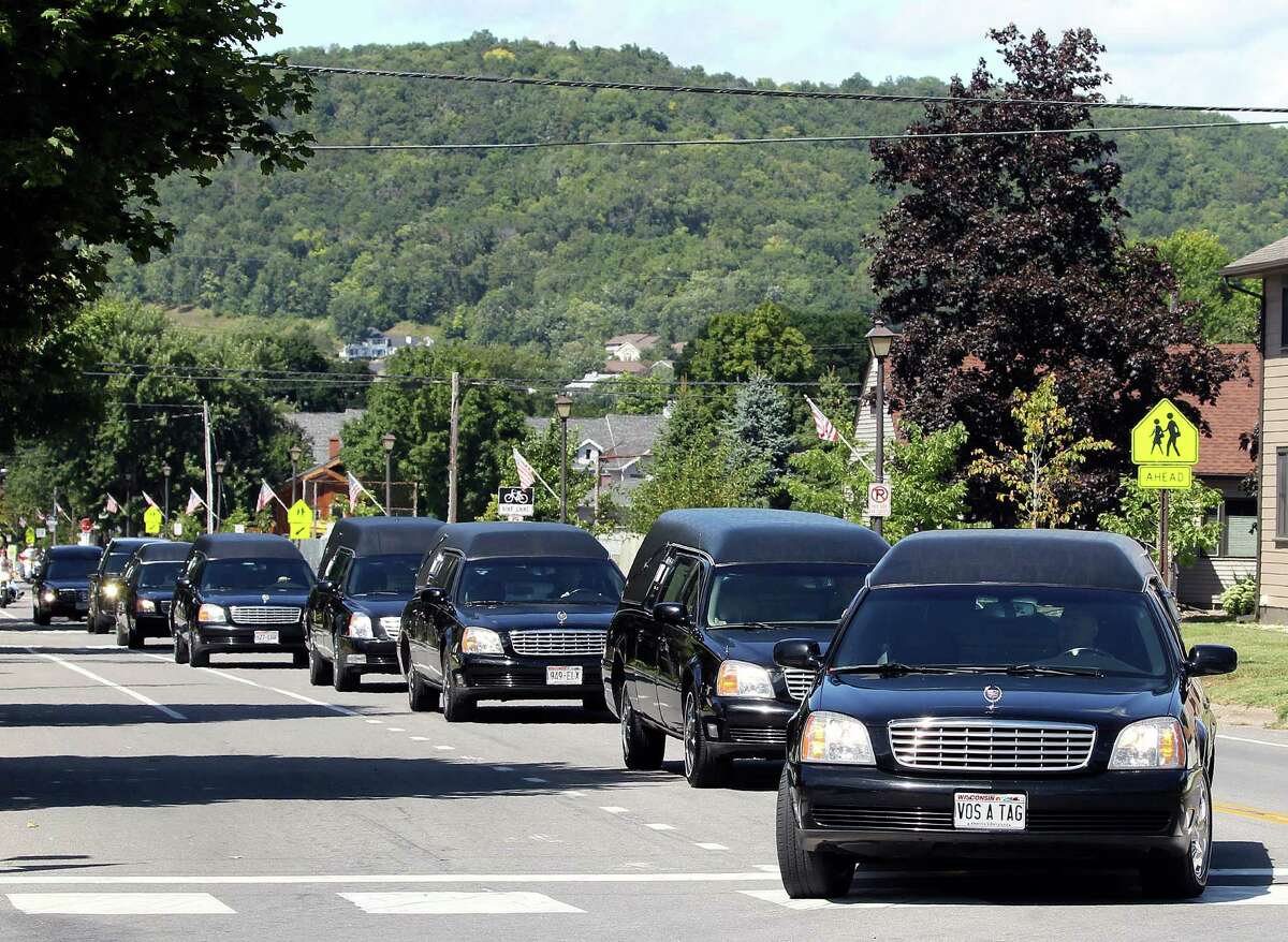 Eight hearses carrying each of the family members killed in the Aug. 8, shooting in Houston, travel from United Methodist Church in La Crescent, Minn., to Prince of Peace Cemetery on Thursday.
