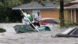 Elvin Duckworth, left, Jonathan Harvey, center, and Leonard Harvey paddle a row boat through a flooded street in their Gulfport, Miss, neighborhood after Hurricane Katrina struck the Gulf Coast Monday,  Aug. 29, 2005 .
