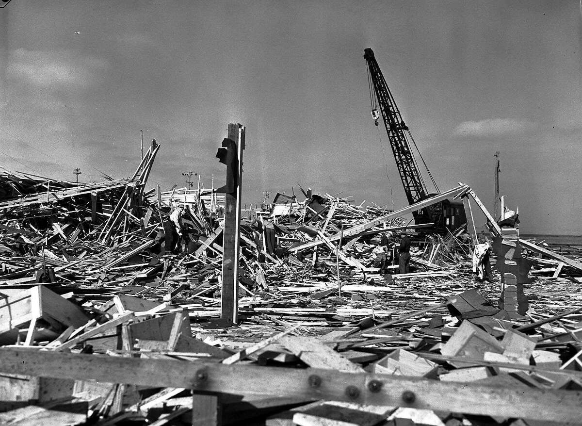 ** FILE ** In this file photo, workmen search through what was the carpenter shop on the pier at Port Chicago, Calif., after the building was leveled by the explosion of two munitions ships the evening of July 17,1944. The site of the World War II explosion that killed 320 people, over 200 of them black sailors, raised enough outrage about the treatment of the black survivors to encourage desegregation of the Armed Forces could become part of the National Park System under a new bill. (AP Photo/File) Ran on: 07-30-2007 Before the explosion, Navy workers loaded ammunition into a ship's cargo net at Port Chicago.