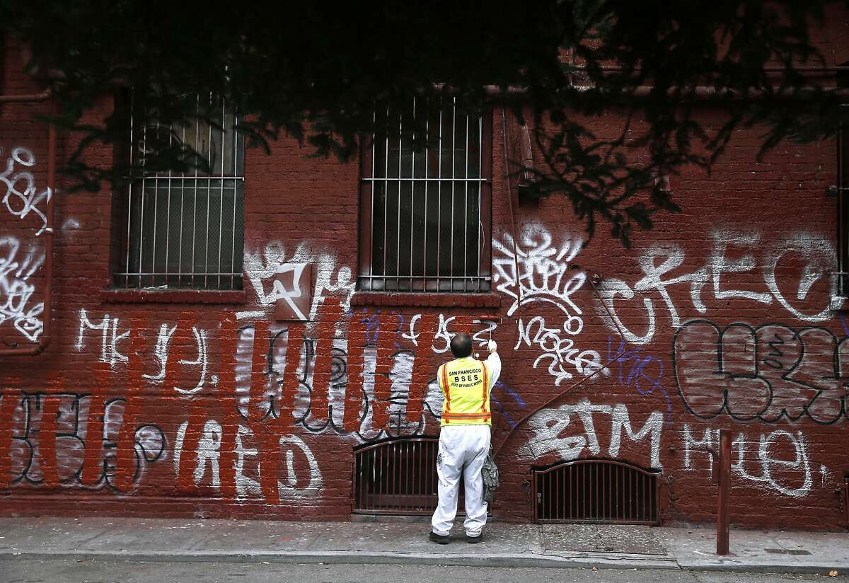 Yu Cheng of the Department of Public Works paints over graffiti covering a building in Chinatown's Quincy Alley, across from St. Mary's Square park, in San Francisco, Calif. on Friday, Aug. 21, 2015. The city attorney's office is suing a serial tagger known as Cozy Terry and is seeking more than $50,000 in damages for repeatedly defacing city property.