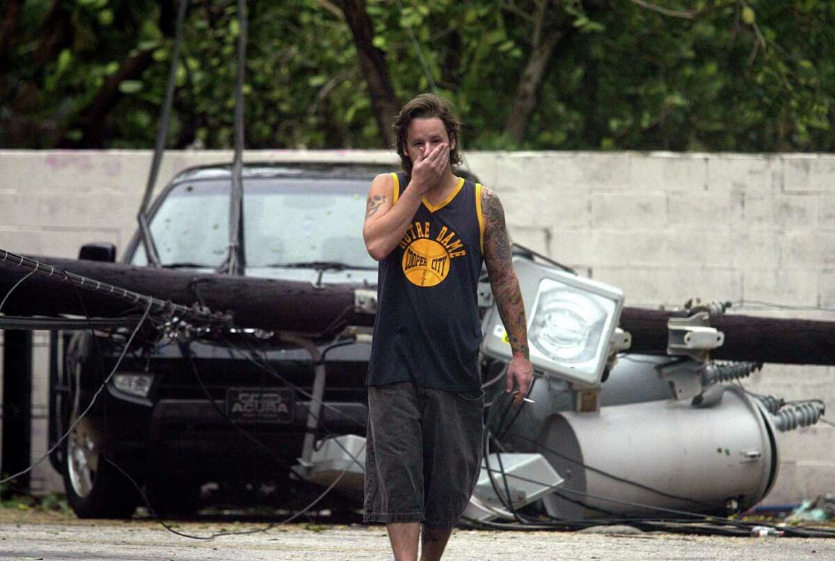 FT. LAUDERDALE BEACH - A man walks away from a car demolished by a falling power pole and transformer brought down in Hurricane Katrina's high winds off NE 9th St in Ft. Lauderdale Beach Friday, Aug. 26, 2005. Two electrical poles in this parking lot were downed in the storm Thursday night, both of them crashing into parked cars with their transformers. Associated Press