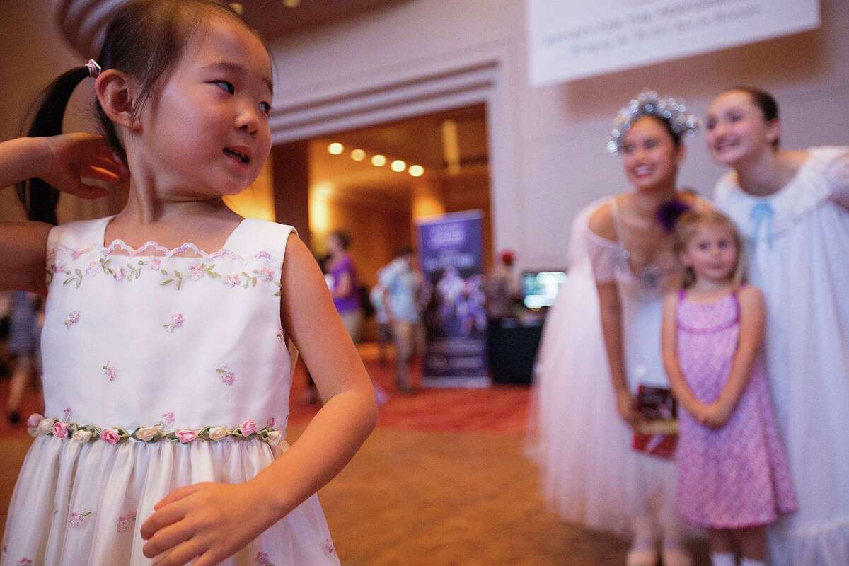 Tiffany Wang, 5, looks back at the Houston Ballet dancers after having her photo taken with them at the Wortham Theater Center during the 21st Theater District Open House Sunday, Aug. 24, 2014, in Houston. The open house featured, music, dance and theater arts as well as activities for children. The event highlights the performing arts in Houston. ( Johnny Hanson / Houston Chronicle )