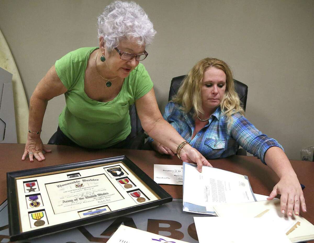 Darlene Stosik, left, looks over items from her brother, Pfc. Geoffrey Saunders, who was killed in Vietnam in 1968. Meghan Burns, right, found them. ﻿