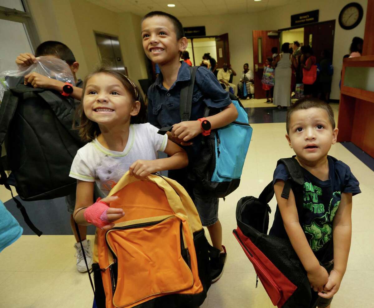 Siblings Rigoberto Romeo, 10, left, Aaliyah Romeo, 6, Angela Romeo, 9, and Hugo Romeo, 4, right, recieve backbacks during the fourth annual Back-to-School Extravaganza at Bethel's Place Empowerment Center, 12660 Sandpiper Dr., Friday, Aug. 21, 2015, in Houston. ( Melissa Phillip / Houston Chronicle )