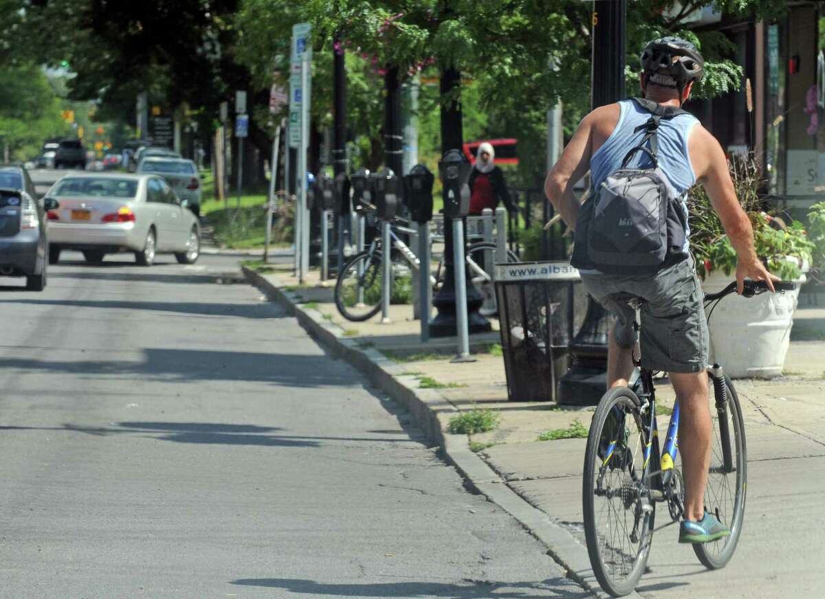 A man bicycles down Madison Avenue on Friday Aug. 21, 2015 in Albany, N.Y. (Michael P. Farrell/Times Union)