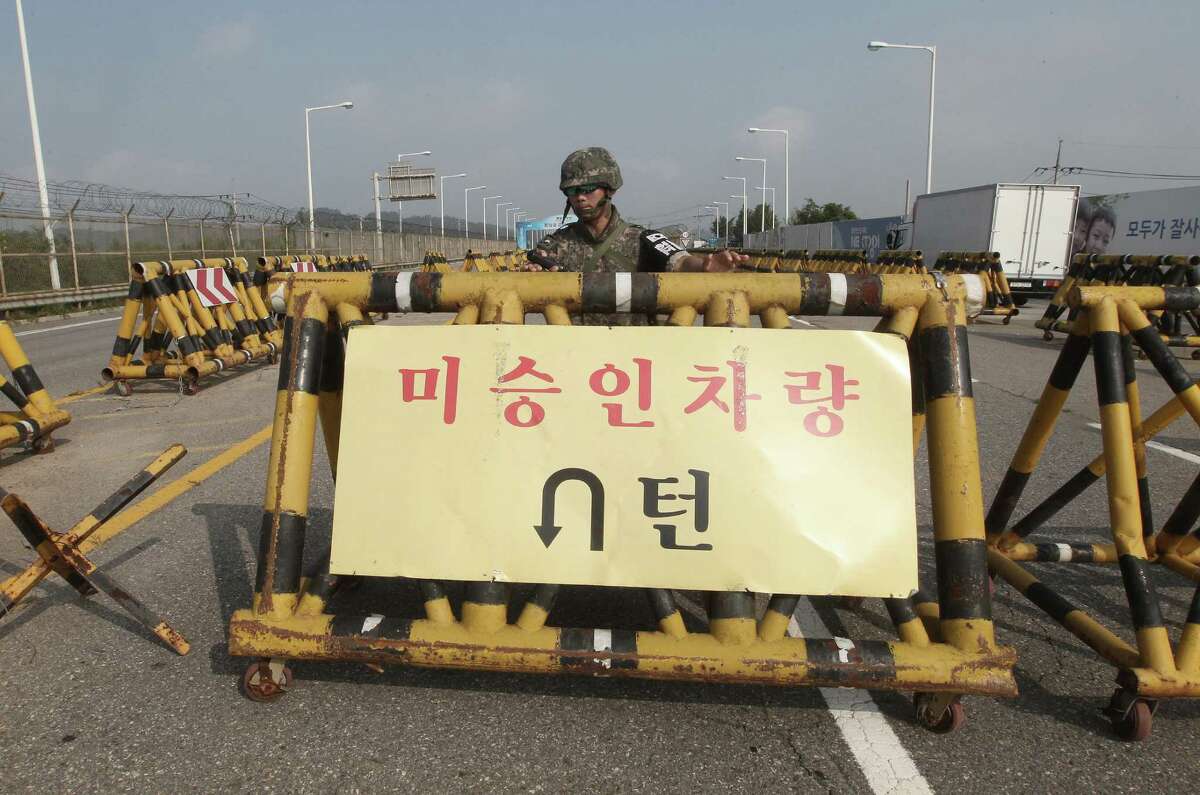 A South Korean amy soldier stands guard behind a barricade on Unification Bridge, which leads to the demilitarized zone, near the border village of Panmunjom in Paju, South Korea, Saturday, Aug. 22, 2015. The letters at a banner read " Disapproved Vehicles". South Korea and North Korea agreed Saturday to hold their first high-level talks in nearly a year at a border village to defuse mounting tensions that have pushed the rivals to the brink of a possible military confrontation. (AP Photo/Ahn Young-joon)
