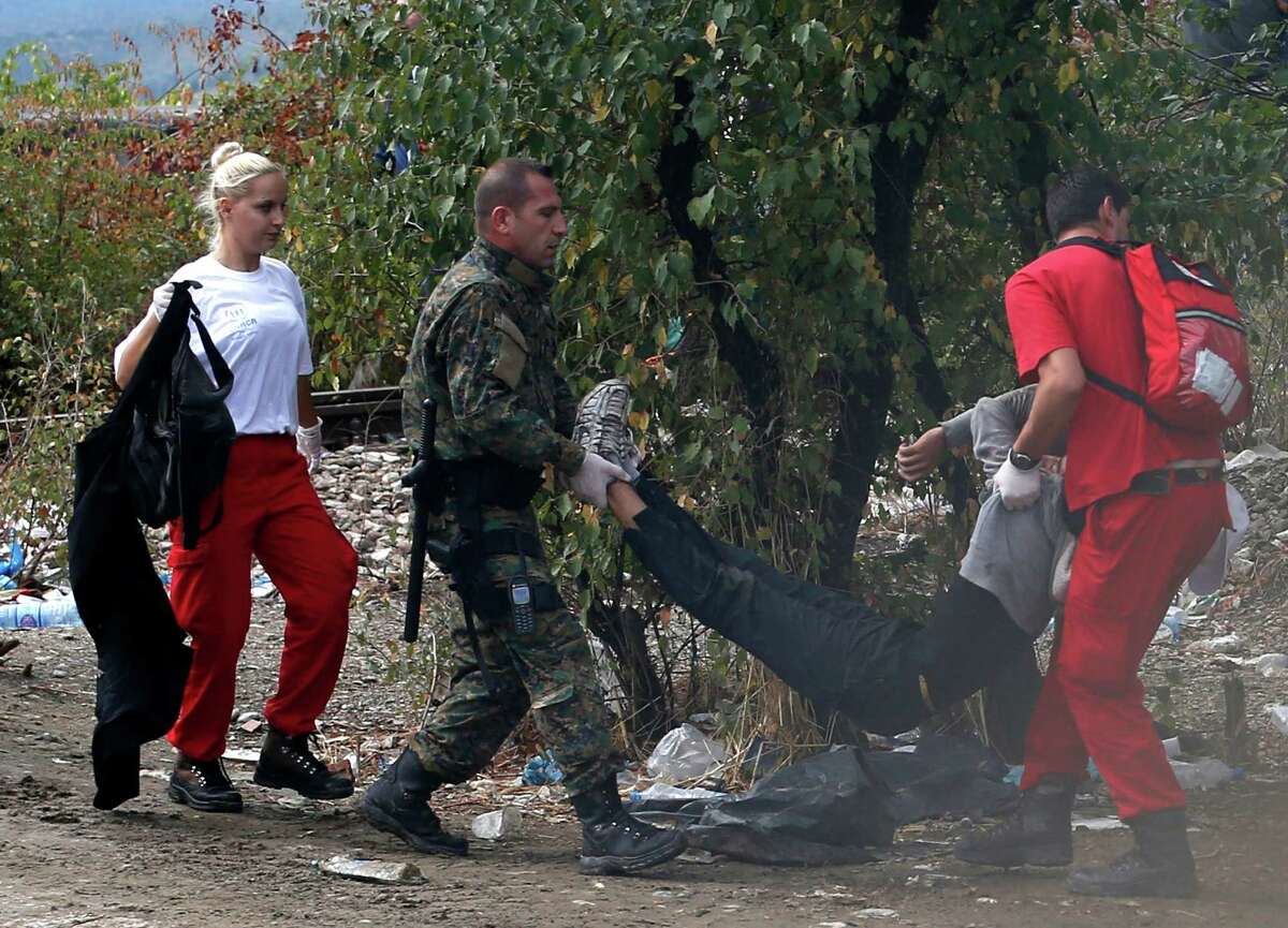 A Macedonian police officer and red cross workers help to a wounded migrant on the border line with Greece, near the train station of Idomeni, northern Greece, Saturday, Aug. 22, 2015. About 39,000 people have been registered as passing through Macedonia in the past month, twice as many as the month before. (AP Photo/Darko Vojinovic)