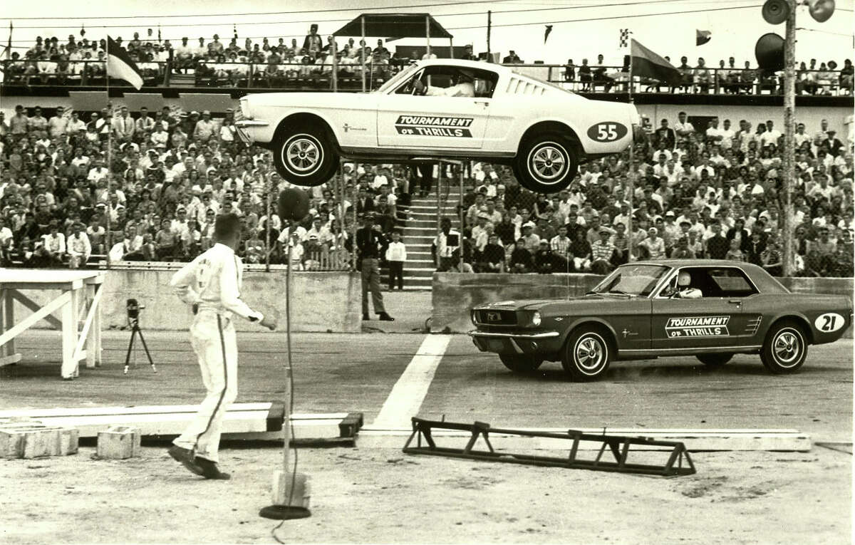 A Ford Mustang flies through the air at the auto thrill shows stage at the Pan American Speedway on Austin Highway. Auto thrill shows attracted audiences with death-defying jumps and intentional crashes by professional stunt drivers. The Pan American Speedway was a longtime venue for these exhibitions.