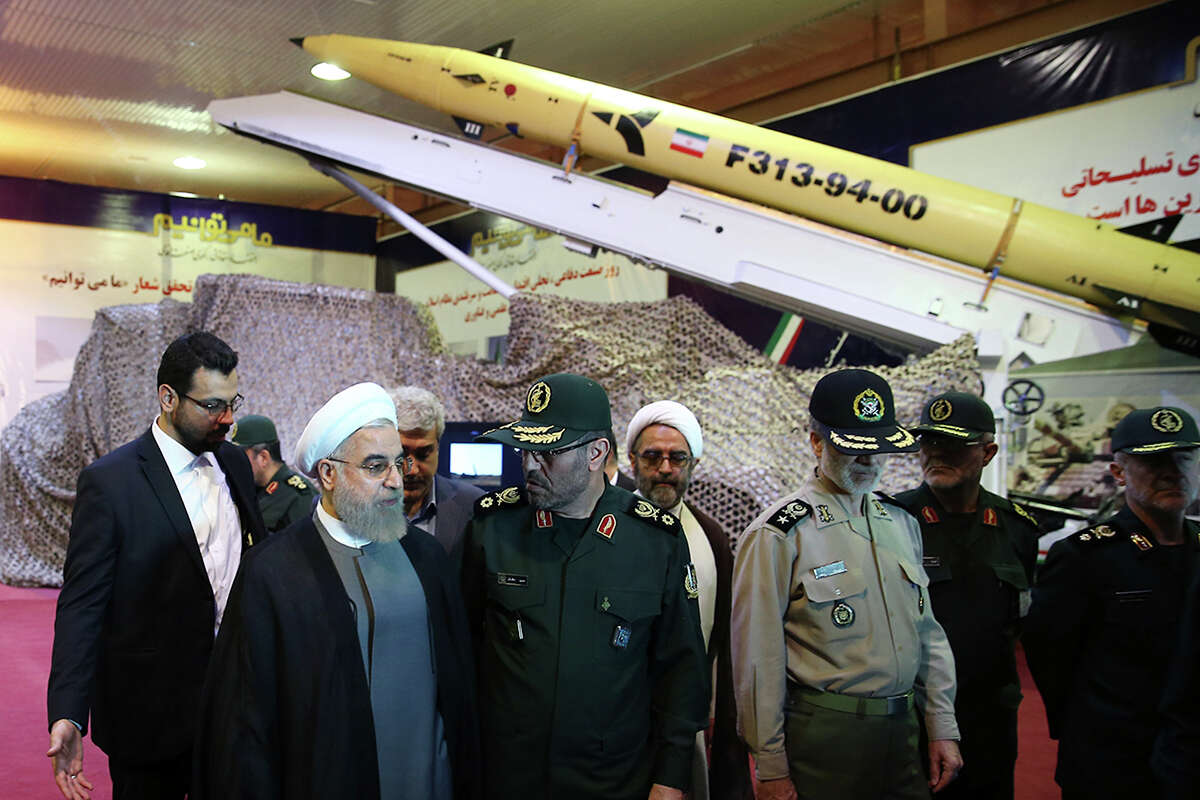 In this photo released by the official website of the office of the Iranian Presidency on Saturday, Aug. 22, 2015, Iran's President Hassan Rouhani, second left, speaks with Defense Minister Hossein Dehghan after unveiling the surface-to-surface Fateh-313, or Conqueror, missile in a ceremony marking Defense Industry Day, Iran. Iran unveiled a short-range solid fuel ballistic missile Saturday, an upgraded version that the government says can more accurately pinpoint targets. (Iranian Presidency Office via AP)