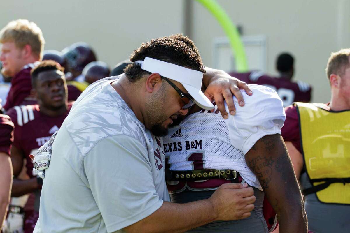 Mikado Hinson prays with Texas A&M football player Josh Walker. Hinson serves as the team's director of player development, acting as a sort of mentor and life coach for the players.