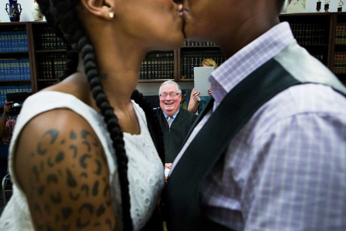 Erikka Givens, left, and Hattie Givens, right, share a kiss after Judge Dale Gorczynski, center, pronounce them wife and wife.