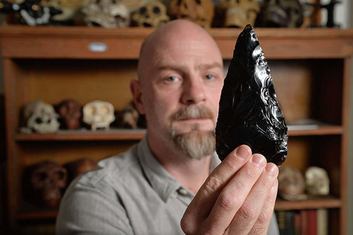 Daniel Adler, an associate professor of anthropology at the Univesrity of Connecticut, holds a stone tool of the type he will be discussing at the Bruce Museum in Greenwich.