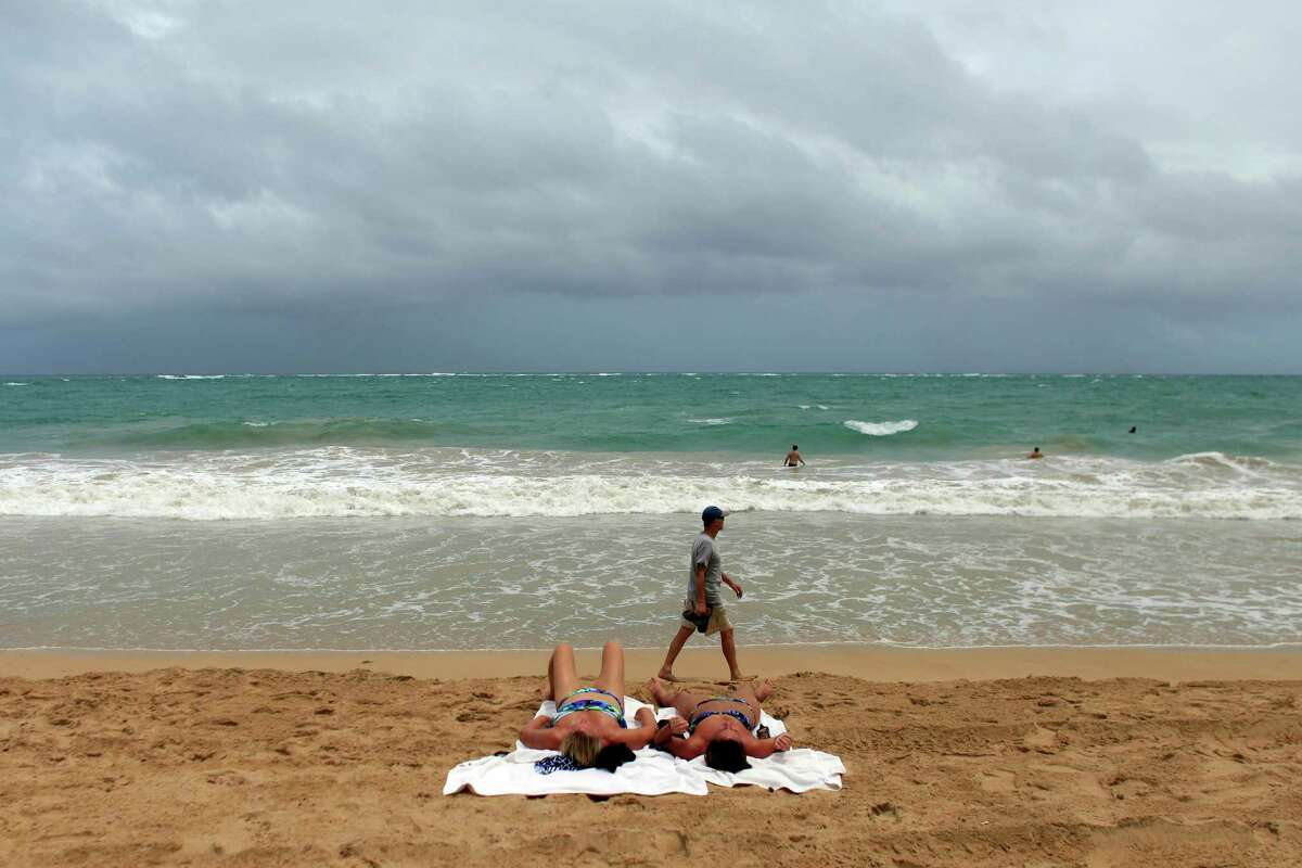 Tourists warily eye skies darkened by Tropical Storm Erika as the system bears down on Luquillo, Puerto Rico, on Thursday. , Aug. 27, 2015. Tropical Storm Erika pummeled the eastern Caribbean island of Dominica, unleashing landslides and killing at least four people. The storm knocked out power and water supplies and had dumped 15 inches of rain on Dominica by early Thursday, according to the weather service in the nearby island of Antigua. (AP Photo/Ricardo Arduengo)