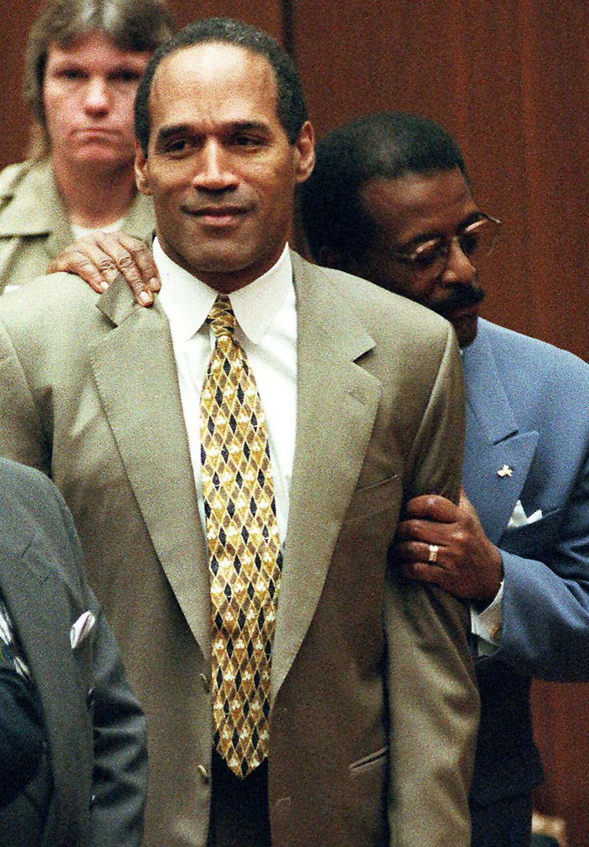 FILE - In this Oct. 3, 1995 file photo, attorney Johnnie Cochran Jr. holds onto O.J. Simpson as the not guilty verdict is read in a Los Angeles courtroom. Simpson's former manager has been ordered by a Los Angeles County judge Monday, June 15, 2009, to keep the former football star's so-called acquittal suit in storage until it is determined who rightfully owns it. (AP Photo/Pool, Myung J. Chun)