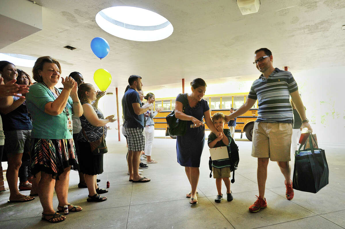 Gavin Cooper, 4, is escorted into Roxbury Elementary School by his parents, Gorden Cooper and Kahla Cooper, during the Clapping In ceremony for kindergarteners at Roxbury Elementary School in Stamford, Conn., on Friday, Aug. 28, 2015. Friday was the first day of school for the the new students.