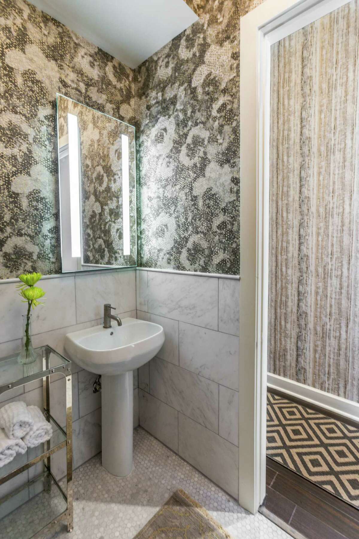 Designer Laura Umansky used a metallic floral-print wallpaper for this powder room in a Heights mid-rise. The metallic tones fit the industrial feel of the condo, but the floral print softens the look.