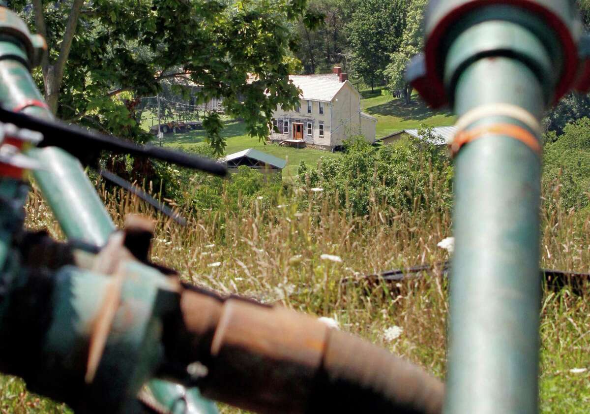 This July 27, 2011 file photo shows a farmhouse in the background framed by pipes connecting pumps where the hydraulic fracturing process in the Marcellus Shale layer to release natural gas was underway at a Range Resources site in Claysville, Pa. In Pennsylvaniaâs fracking boom, new and more unconventional wells leaked far more than older and traditional wells, according to a study of inspections of more than 41,000 wells drilled. And that means that that methane leaks could be a problem for drilling across the nation, said the author of the study, which funded in part by environmental activist groups and criticized by the energy industry. The study was published Monday by the Proceedings of the National Academy of Sciences. (AP Photo/Keith Srakocic, File)
