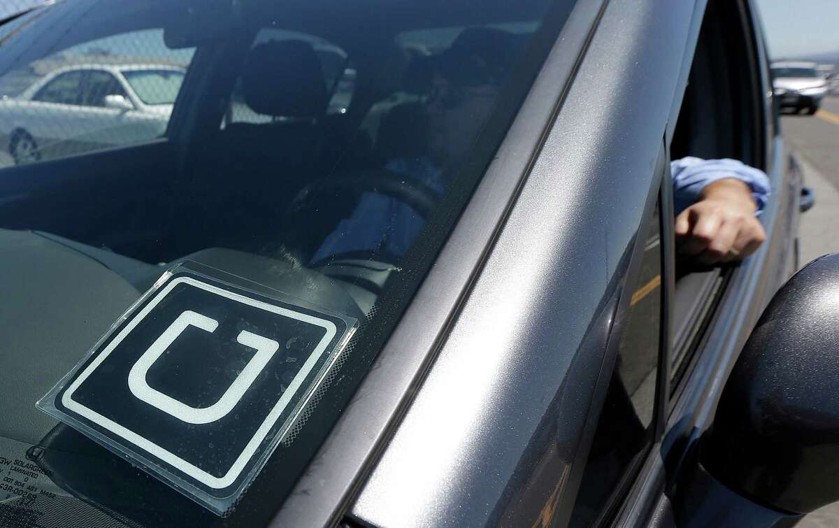 Uber driver Karim Amrani sits in his car parked near the San Francisco International Airport parking area in San Francisco in July. On Tuesday, a federal judge granted Uber drivers class-action status in their case against the company.