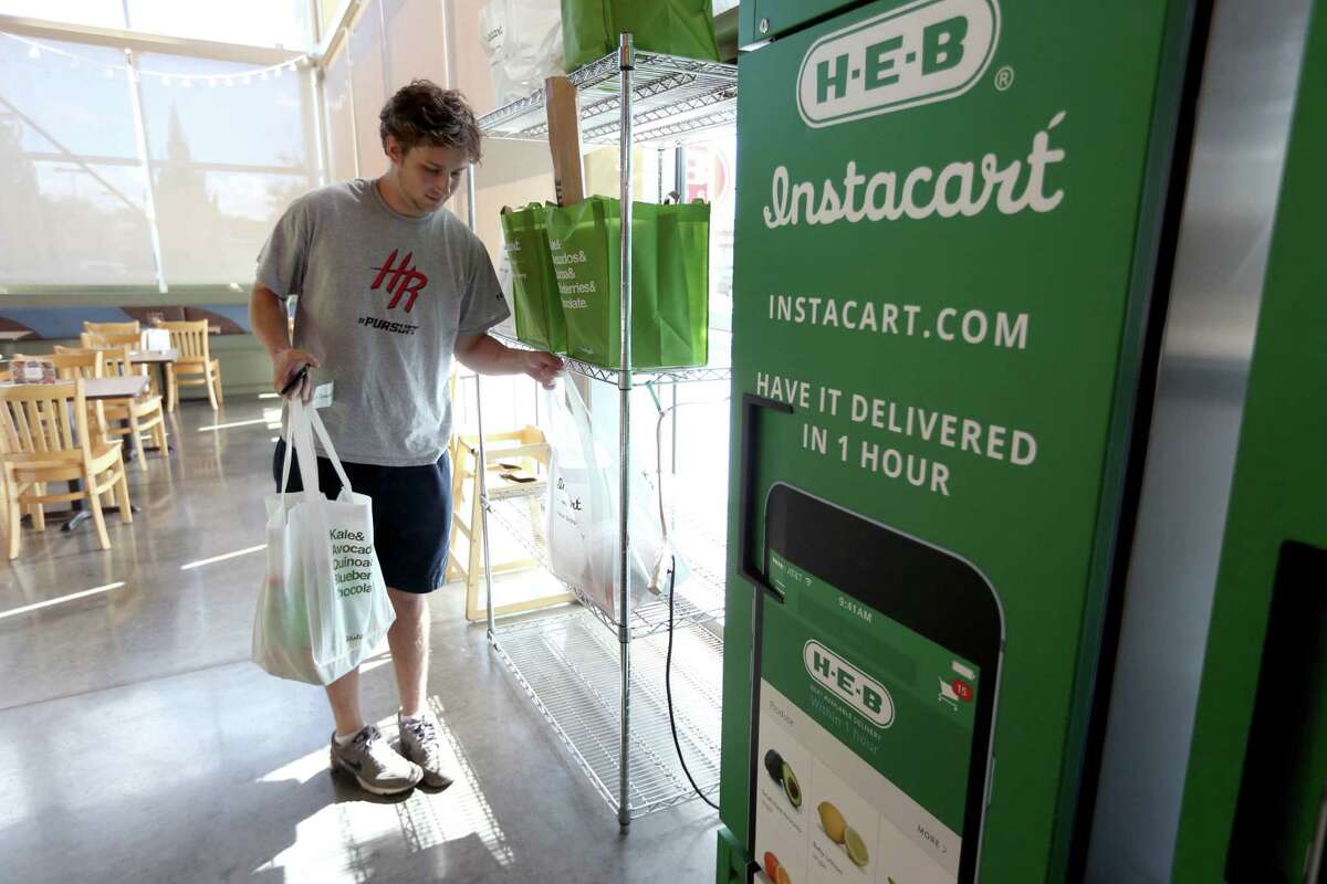 Douglas Gates, an Instacart employee, gathers items from an Instacart staging area at an H-E-B to be delivered to a home. ﻿