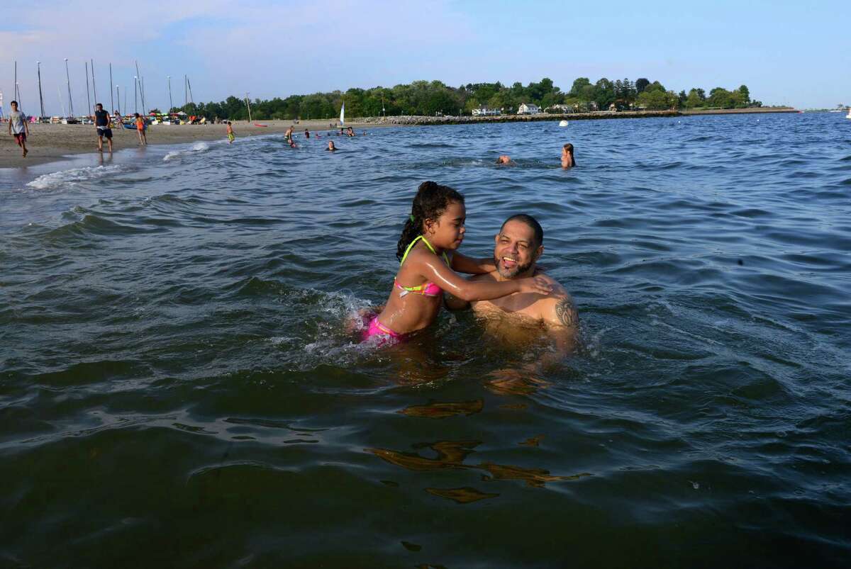 Elaine Cano, 8, of New York City, and family friend Edward Rodriguez, play in the water while at Jennings Beach in Fairfield last month. Beach closings have increased in the past five years, with Jennings Beach closing more often than others along the western Connecticut coastline.