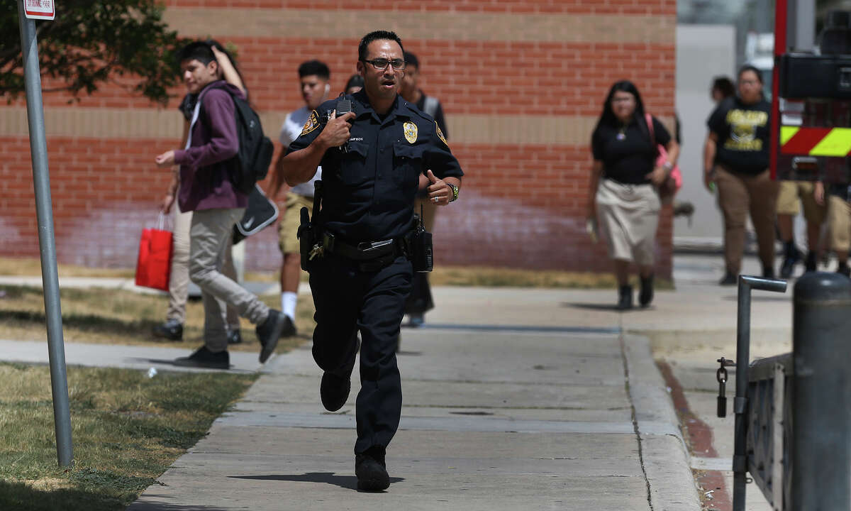 A police officer runs down a sidewalk Friday September 4, 2015 at Edison High School where the San Antonio Fire Department was called about noon. San Antonio Independent School District spokesperson Leslie Price said a junior at the school somehow became locked in a safe in the school's ROTC area. Price said firefighters have drilled holes in the combination safe and that the student's parents have been notified.