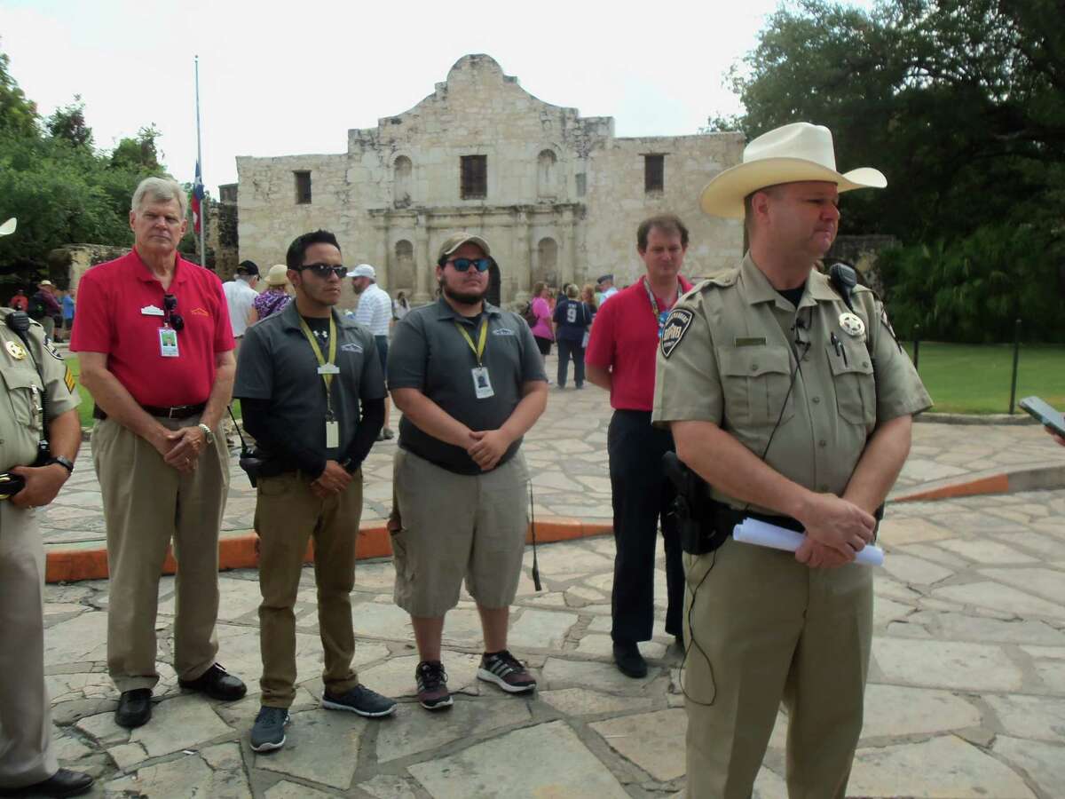 Alamo Rangers Chief Mark Adkins speaks Friday to the media about Thursday’s desecration of part of a wall in the mission-era church, with tour guides and other employees at the state shrine behind him.