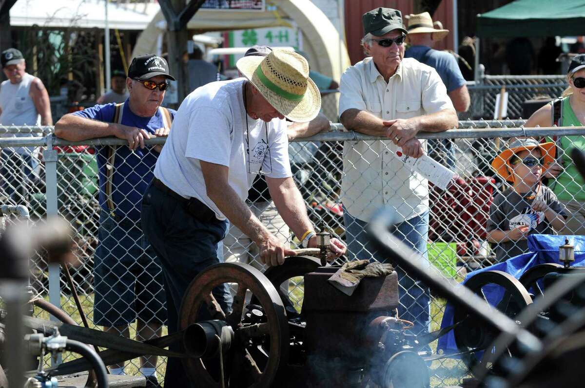 Howard Houck of Ballston Spa, center, polishes the fly wheel of a 1925 three-horsepower economy engine at the Early Engine Club area during the Schaghticoke Fair on Saturday, Sept. 5, 2015, at the Schaghticoke Fairgrounds in Schaghticoke, N.Y. The fair continues through Monday from 10 a.m. to 10 p.m. Visit www.schaghticokefair.com for more information. (Cindy Schultz / Times Union)