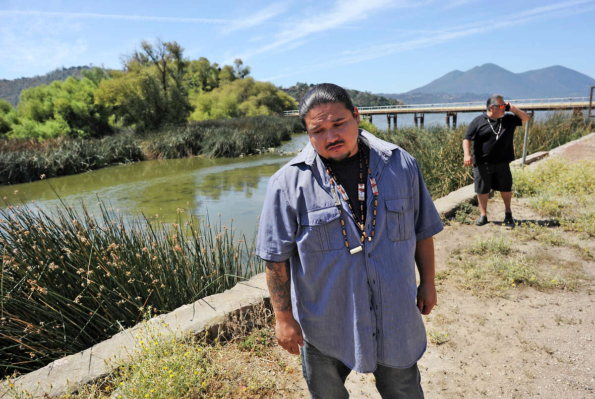 Rob Morgan, Koi Nation tribal historical preservation officer, describes the looting of Native American sites, with fellow tribal official Dino Beltran behind him on the shore of Clear Lake.