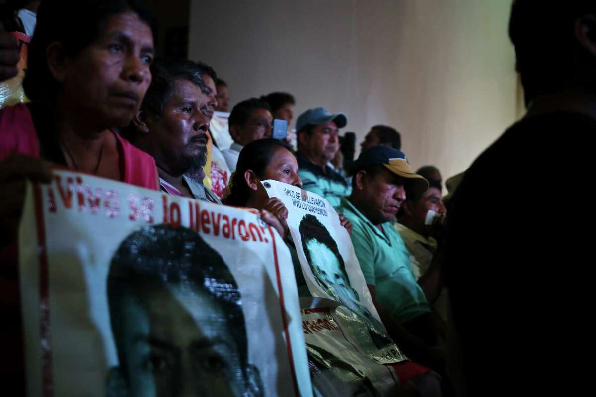 Parents of the 43 teachers' college students hold up images of their missing sons as they listen in to a conference in Mexico City, Sunday, Sept. 5, 2015. An independent report presented Sunday dismantled the Mexican government's investigation into last year's disappearance of the 43 students, saying the prosecutor's contention that they were incinerated in a giant pyre never happened and fueling the anger of parents who still don't know what happened to their sons. (AP Photo/Emilio Espejel)