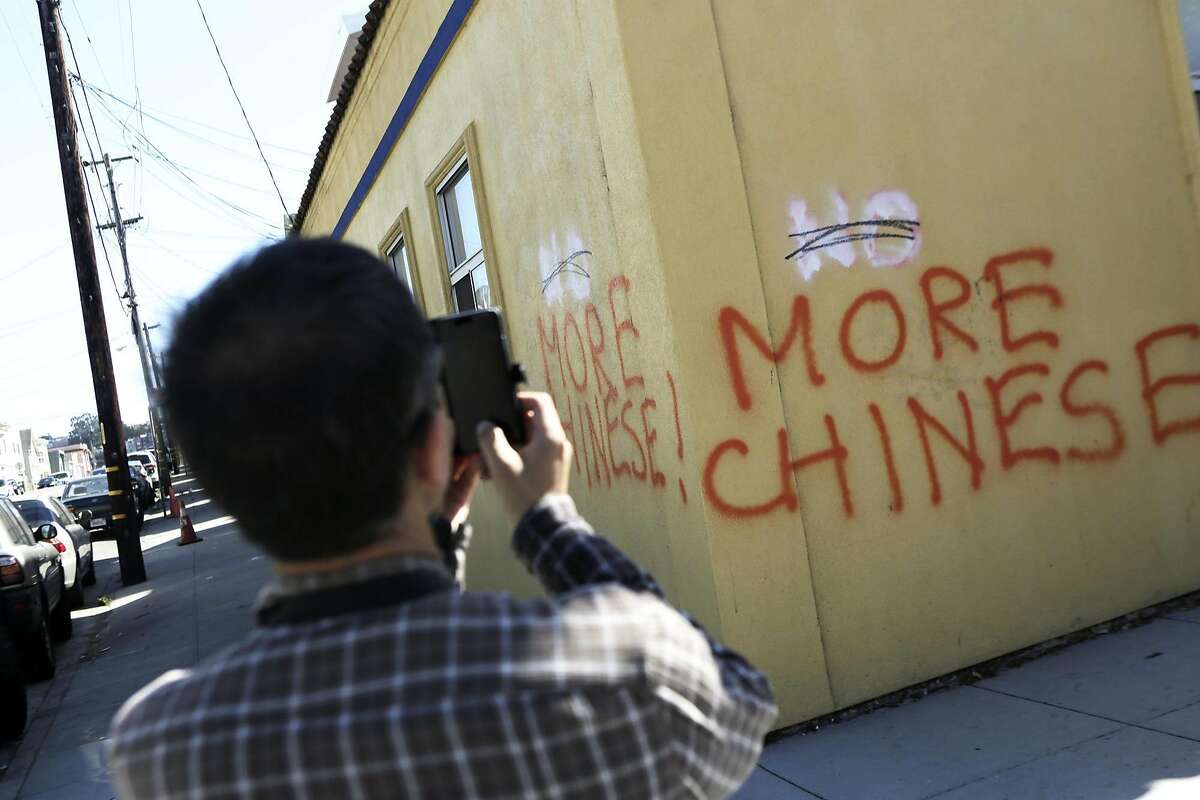 Eric Li of San Francisco stops on his walk home to take a photo of anti Chinese graffiti at the corner of Somerset St. and Silver Ave in San Francisco, Ca. on Monday, September 7, 2015.