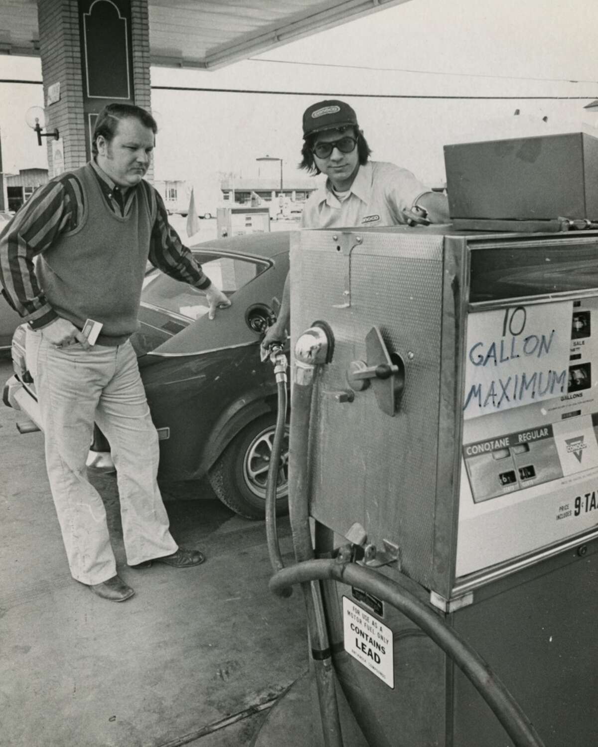 On Dec. 21, 1973, John O. Pickett (left) waits while attendant Ron West pumps gas into Pickett's car at the Westchester Conoco station on Memorial Drive at Dairy Ashford Street in Houston. The station limited sales over the holiday weekend to 10 gallons per customer while most Texas stations closed.