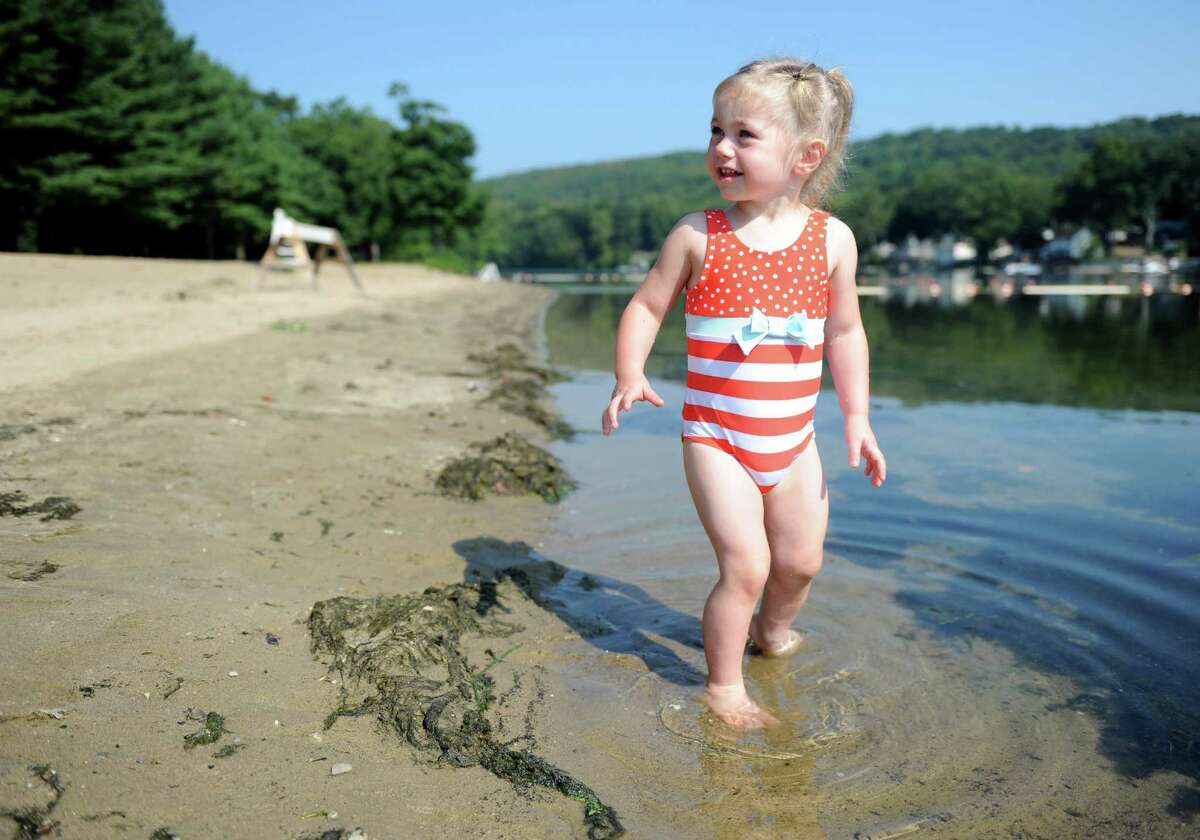 Two-year-old Olivia Branco, of Shelton, dips her feet in the Housatonic River Tuesday, Sept. 8, 2015, at Indian Well State Park in Shelton, Conn. That is as far as Branco could venture in the water as the beach at Indian Well remains closed due to blue-green algae which can produce toxins that could be harmful to humans and dogs.