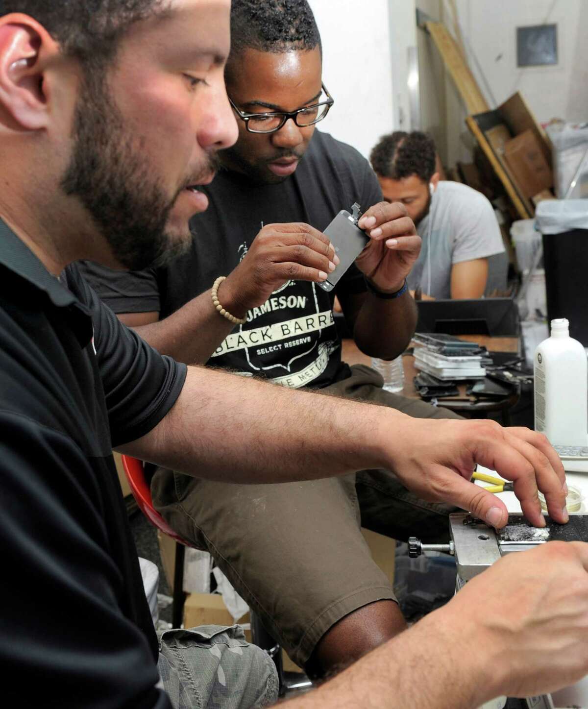 Chris Rice, left, and Dane Jackson make iPhone screens at Mobile Resue on Federal Road in Danbury Tuesday, Sept. 9, 2015.