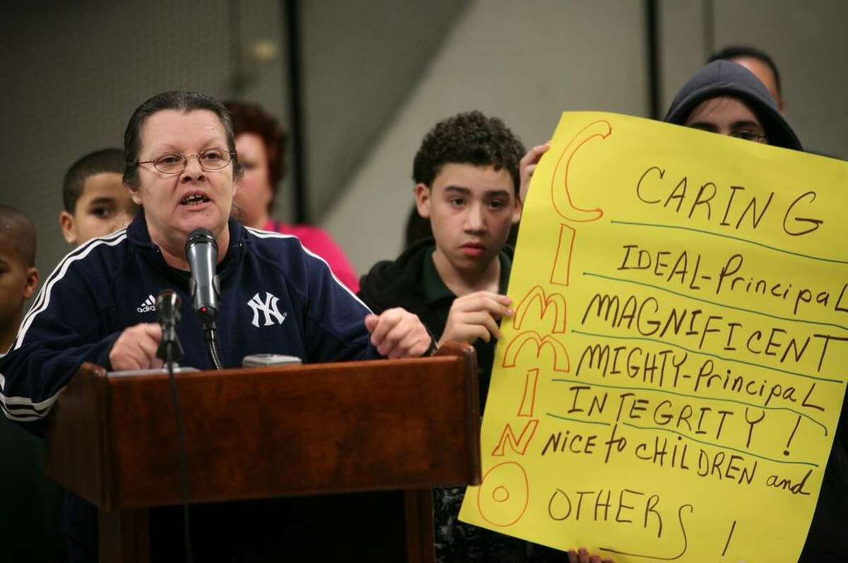 Robin Mastro of Bridgeport addresses the Board of Education in support of Thomas Hooker School principal Andrew Cimmino, on paid leave since September, as Hooker students Edgar Feliciano, 12, and Monet Monterroso hold up a sign, at the Bridgeport Board of Education meeting at the Aquaculture School on Monday, March 22, 2010.