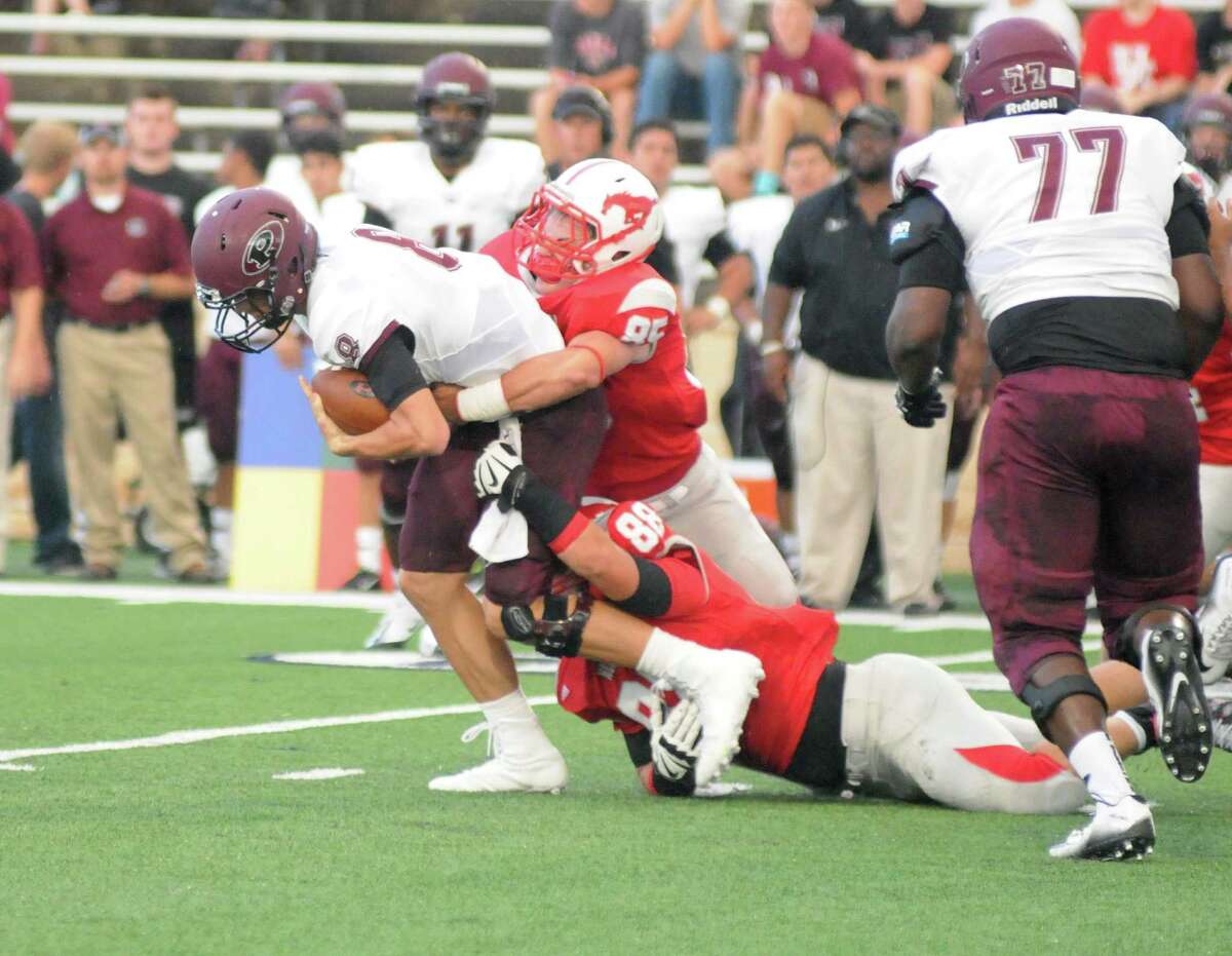 One of Pearland's two quarterbacks, Connor Blumrick (8) surges ahead while being tackled by Houston Memorial players Rudolph Vargas (85) and Daymon Driggs (88) during last week's game.