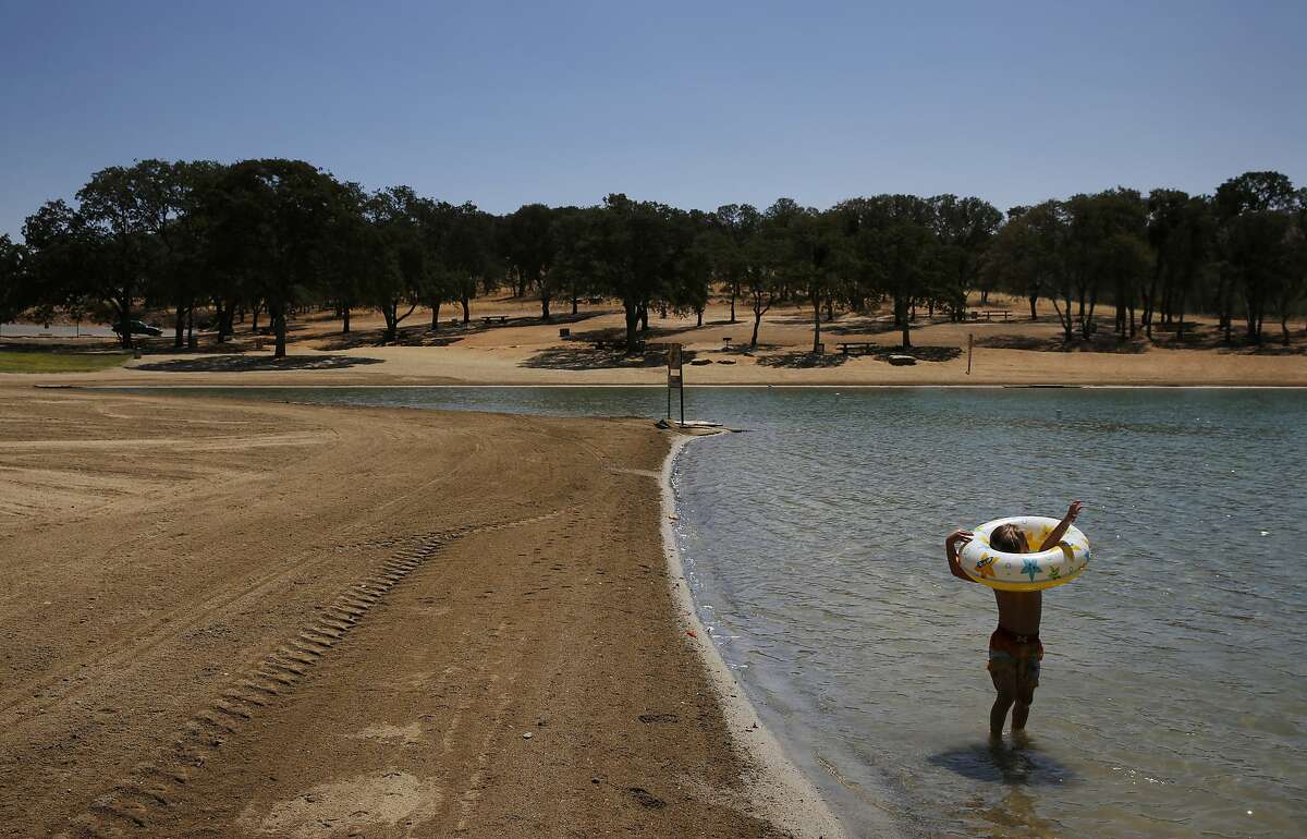 Anthony James Meleen, 3, struggles to get his arms through a floatation device while playing with family in the swimming lagoon at Don Pedro reservoir as it hovers at 32 percent of its total capacity Aug. 19, 2015 in La Grange, Calif.