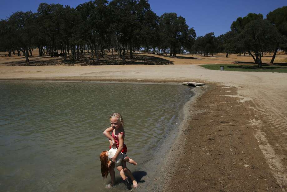 Sofia Danielle Meleen, 4, carries Rose into the water with her as she plays with family in the swimming lagoon at Don Pedro Reservoir, where San Franc isco stashes water during wet years, as it hovers at 32 percent of its total capacity. Photo: Leah Millis, The Chronicle