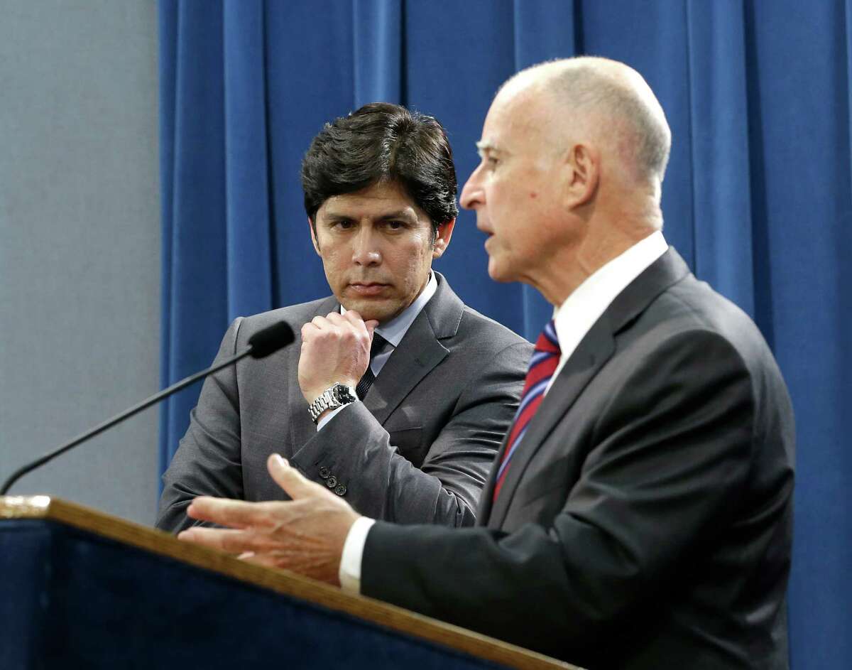 Senate President Pro Tem Kevin de Leon, D-Los Angeles listens as Calif. Gov. Jerry Brown, discusses the scaling back of a proposal to address climate change that he supported during a news conference, Wednesday, Sept. 9, 2015, in Sacramento, Calif. Citing opposition from the oil industry, de Leon, said he was dropping a mandate in his bill, SB350, that the state cut petroleum use by 50 percent.