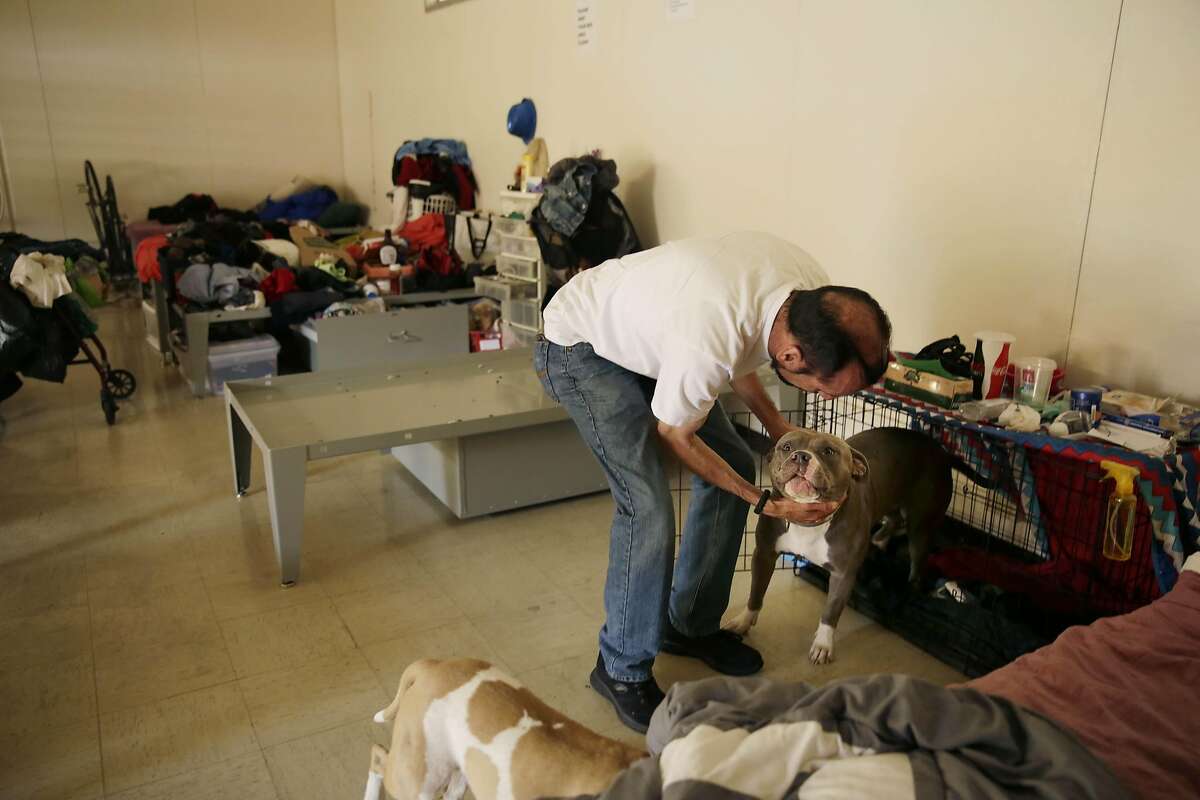 Enrique Gonzalez, pats his dog, Hops, at the Navigation Center on Thursday, September 10, 2015 in San Francisco, Calif. Gonzalez said he became homeless when he was evicted from his residence in April.