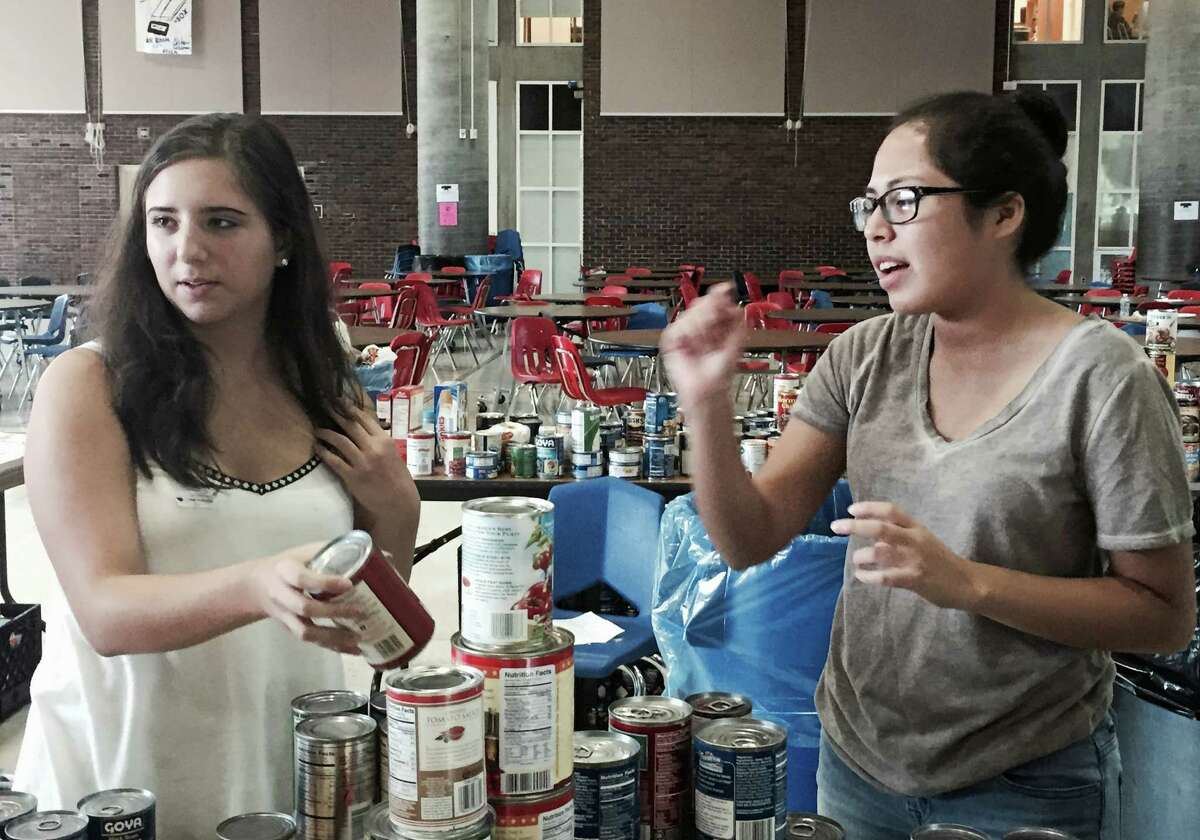 Above, seniors Brianna Musilli, left, and Maria Anyosa, members of Greenwich High School's Roots & Shoots service club, sort canned goods Friday in Greenwich High's student center during the 9/11 food drive. Below, the donated items fill tables.