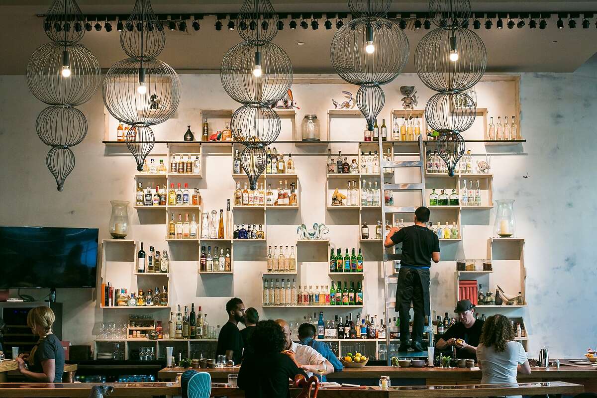 The bar at Calavera in Oakland displays many shelves full of different bottles of mezcal.