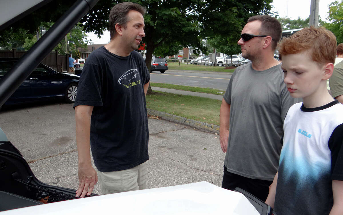Andrew Baumer, left, talks about his 2015 Chevy Volt with Dennis Sullivan and his son, Bran, 12, at Fairfield's First Electric Vehicle Showcase.