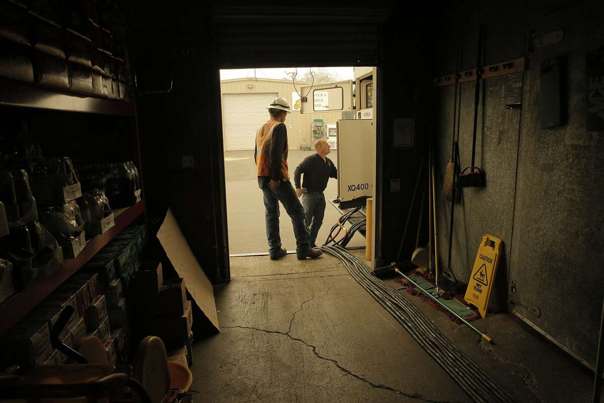 Vince Sigal, right, and Brandon Clark, subcontractors for PG&E, complete connections from a generator to Hardesters Hardware and Market in Middletown, Calif., on Sunday, September 13, 2015, the day after a wildfire swept through town destroying homes and forcing mass evuations. PG&E contacted the store about reconnecting power to the store to serve the community once residents return.