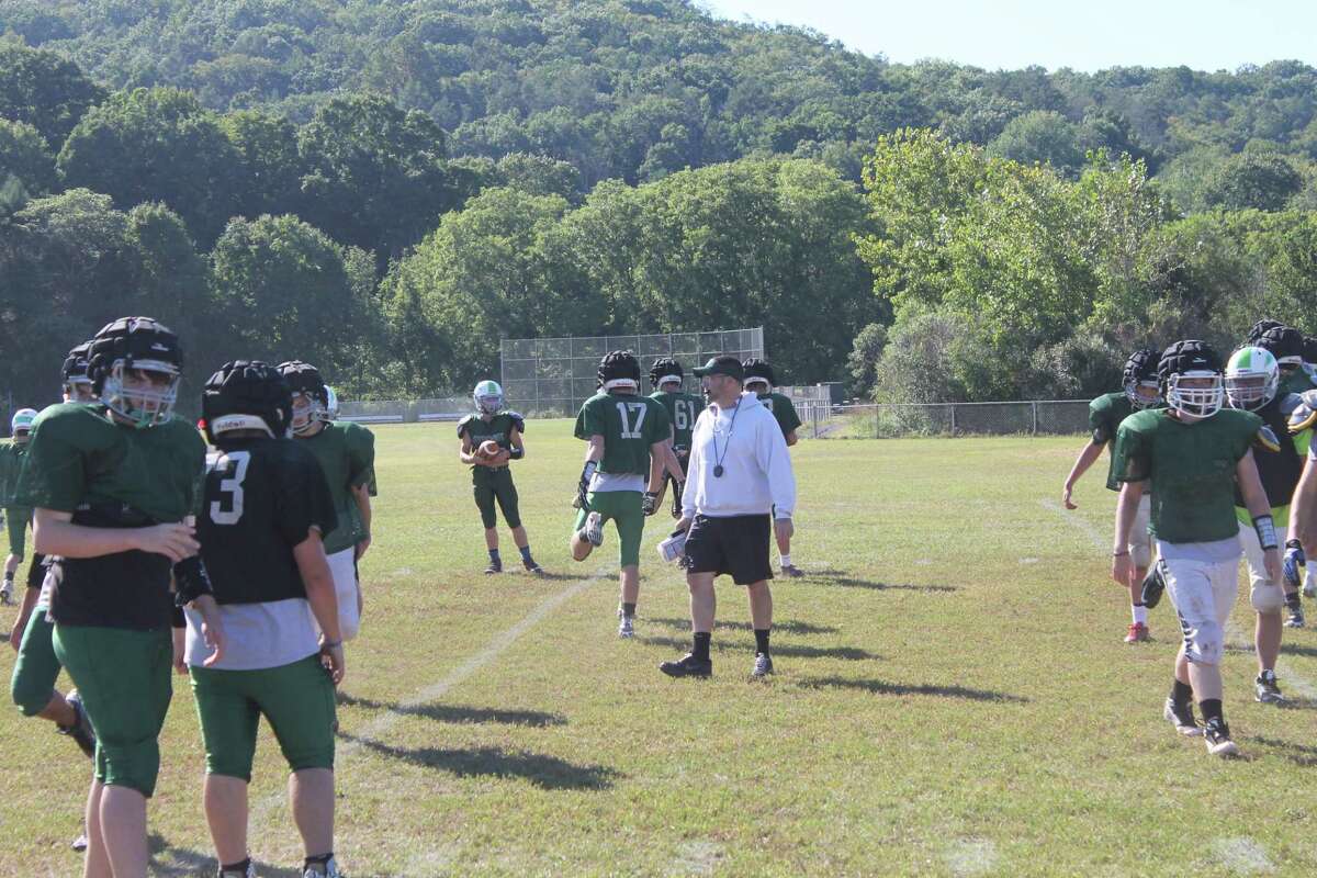 New Milford coach Larry Badaracco moves his squad through warm ups before more preparation for Brookfield. Badaracco said the main goal of the program is to instill a new mentality and change the culture of a program that is not used to winning.