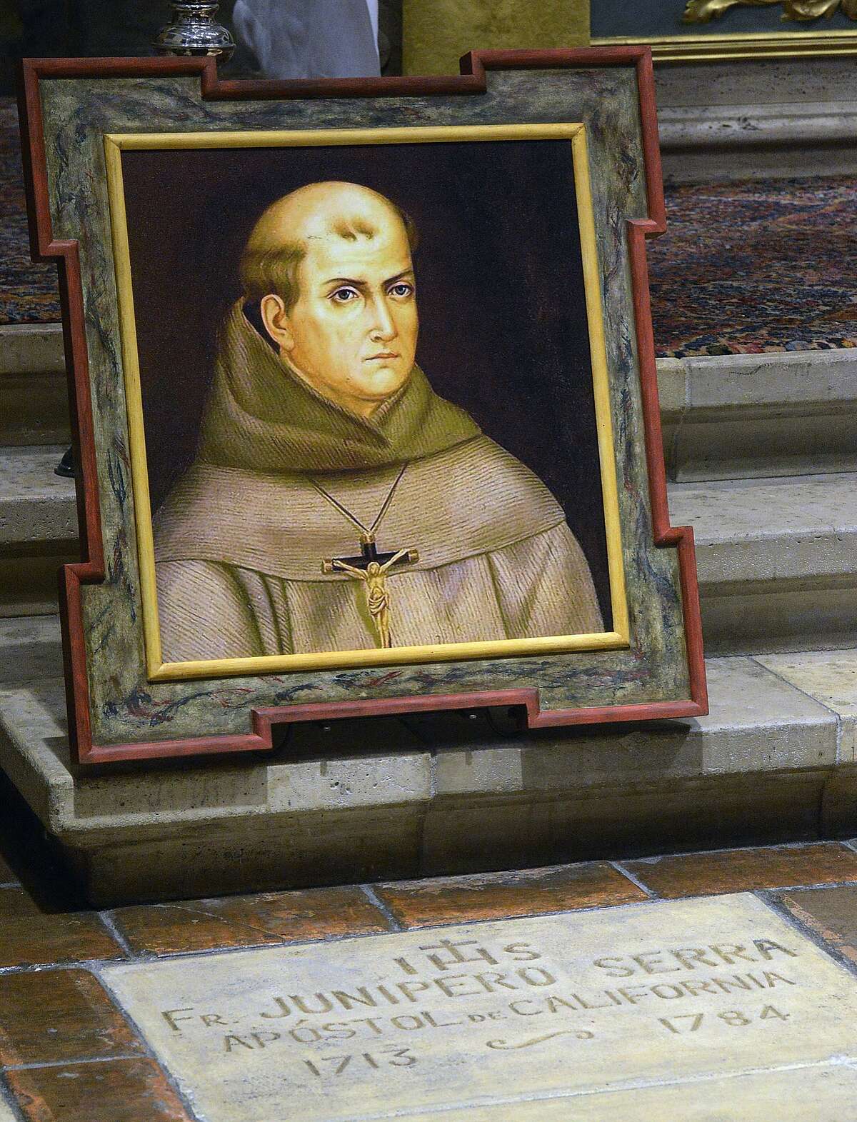FILE - In this May 6, 2015 file photo, a painting of Rev. Junipero Serra is seen above his grave inside the basilica at the Carmel Mission in Carmel, Calif. Pope Francis' apology for the Roman Catholic Church's crimes against indigenous peoples has not softened opposition among some California Native Americans to his decision to canonize 18th-century Franciscan missionary Junipero Serra, extolled by the Vatican as a great evangelizer, but denounced by some tribal officials as a destroyer of Native culture.(David Royal/The Monterey County Herald via AP, File) MANDATORY CREDIT