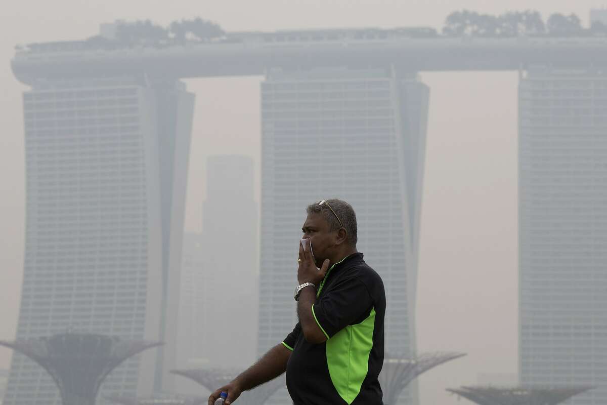 FILE - In this Sept. 10, 2015 file photo, a man covers his nose during a hazy day in Singapore. Air pollution is killing 3.3 million people a year worldwide, according to a new study that includes this surprise: Farming plays a large role in smog and soot deaths in industrial nations.