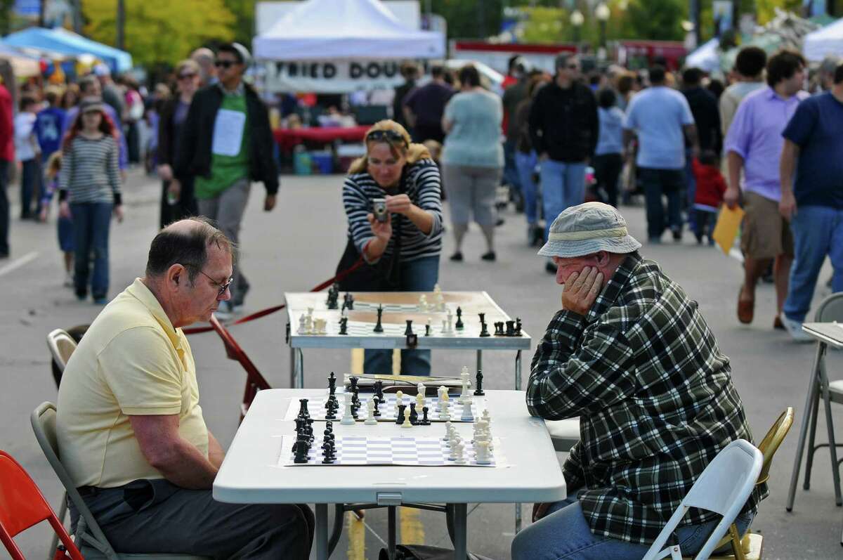Brother John McManus, right, plays chess against Jim Lanpher, left, both of Albany, on a closed off Madison Avenue during the Upper Madison Street Fair on Sunday Sept. 23, 2012 in Albany, NY. Brother McManus is part of The Right Move, an organization that runs free scholastic chess tournaments, including their next one at Albany Academy on October 6, 2012. (Philip Kamrass / Times Union) ORG XMIT: MER2015091510293988