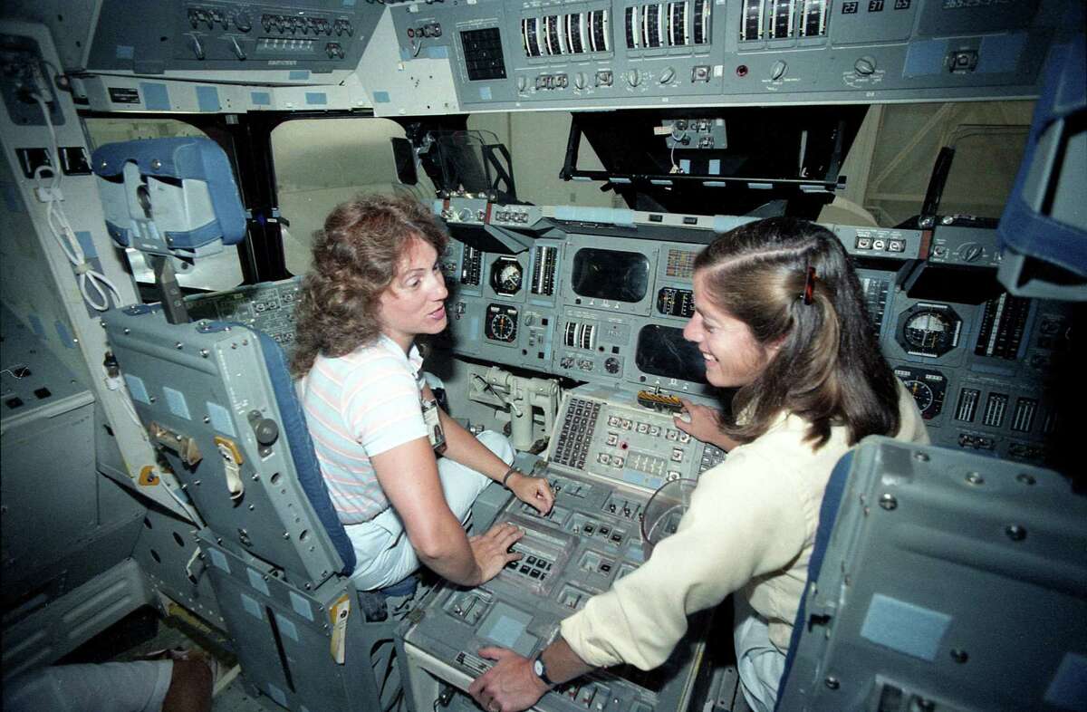 Teacher Christa McAuliffe gets a tour of the space shuttle mockups at the public affairs offices at the Johnson Space Center, Sept. 12, 1985. With her is teacher Barbara Morgan.