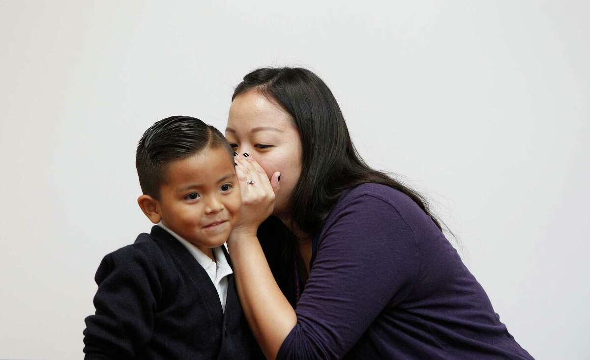 Kinder teacher Vanessa Chang's whispers to Adiel Munoz during a guess the profession game Tuesday, Sept. 15, 2015, in Houston. 