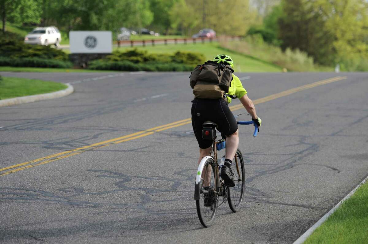 A GE Capital worker biking to work in May 2014 in Danbury, Conn. With General Electric inviting speculation on its future in Connecticut, employees are faced with uncertainty over whether they will be subjected to a transfer to another locale.